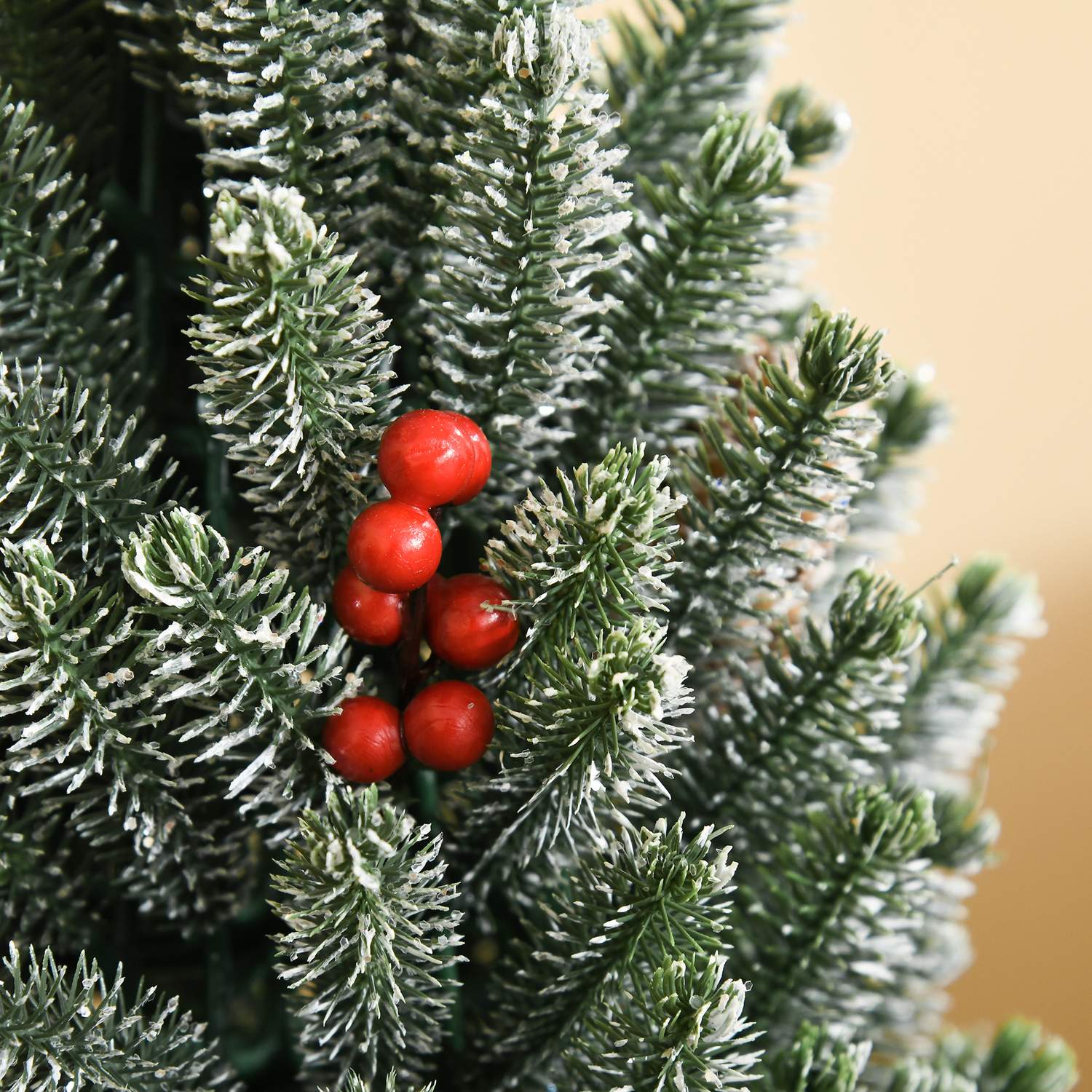 Snötäckt bordsjulgran med bär och tallkottar