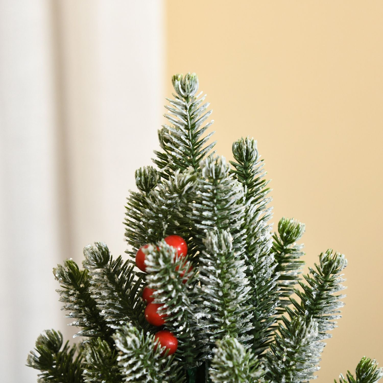 Snötäckt bordsjulgran med bär och tallkottar