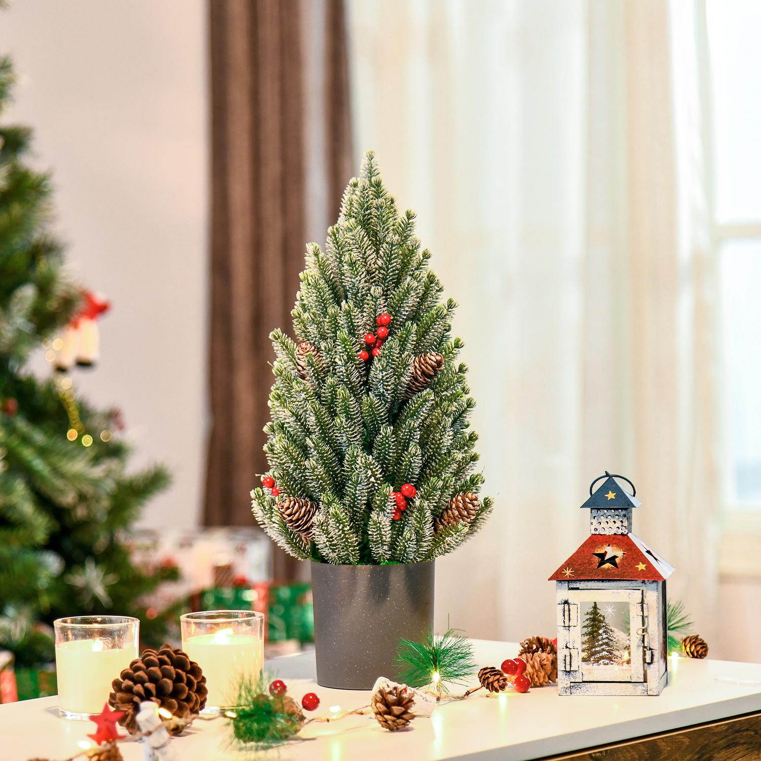 Snötäckt bordsjulgran med bär och tallkottar
